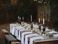 Long wedding reception table set with dinnerware and candle wine bottle decor, 10k budget wedding planning