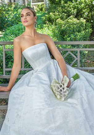 Mia is a timeless A-line gown, crafted from our luxurious Jolie Jacquard. Featuring a straight across neckline to frame the shoulders and face, and a classic silhouette that is ideal for any shape. Elegant pleating starts at the hips and carries around to the back of the skirt creating a regal touch and drawing your attention to the button detailing and 70" Tiffany length train.
