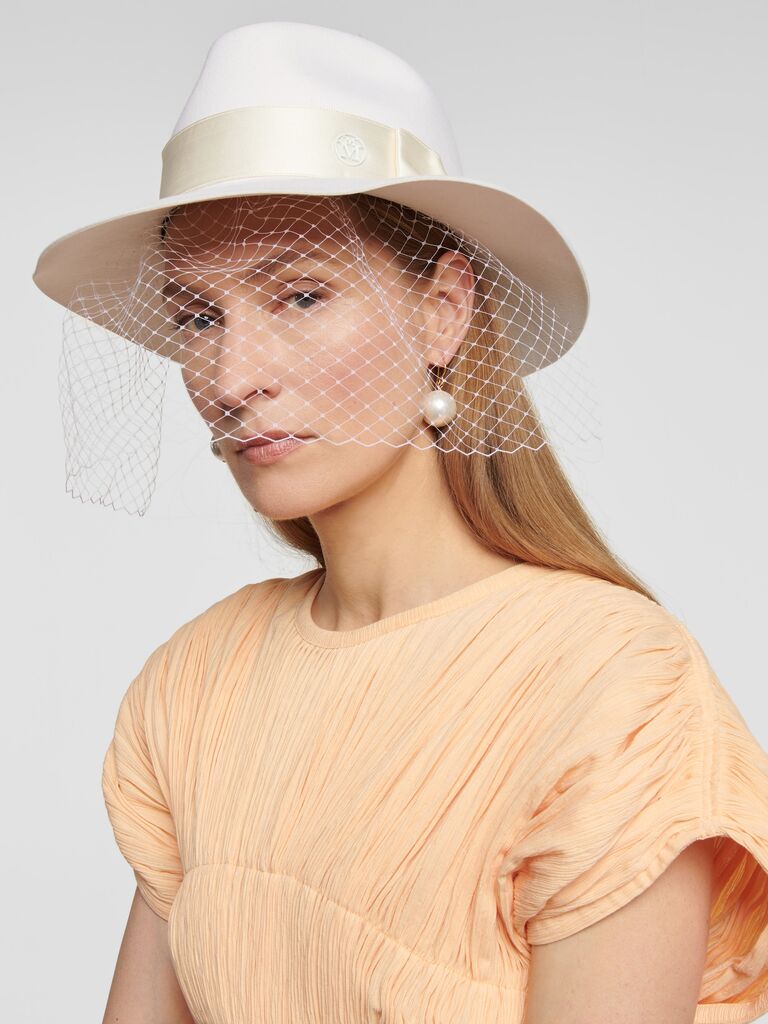 White cowboy hat with birdcage veil by Mytheresa. 